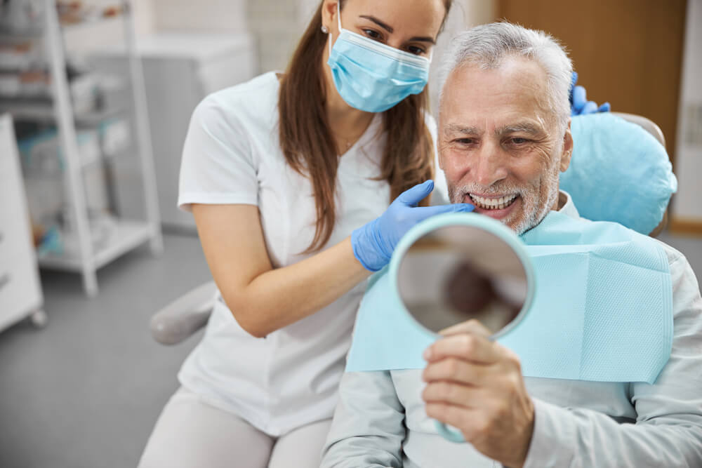 a senior patient with the Best dental Implants in Davie looks in the mirror
