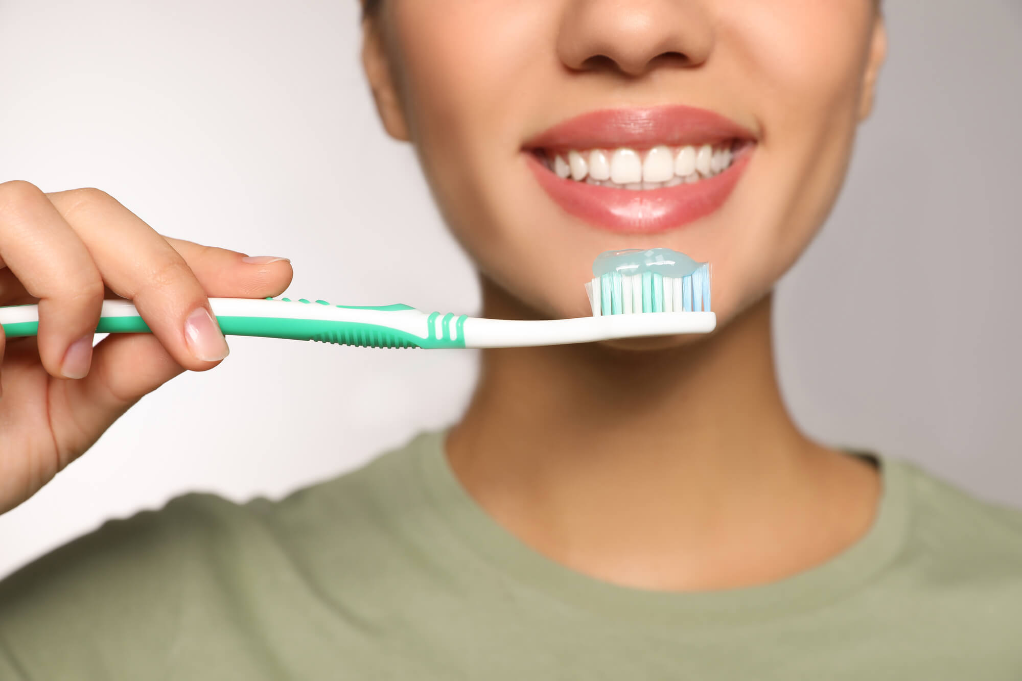 woman about to brush teeth as requested by the best dentist in Davie, FL