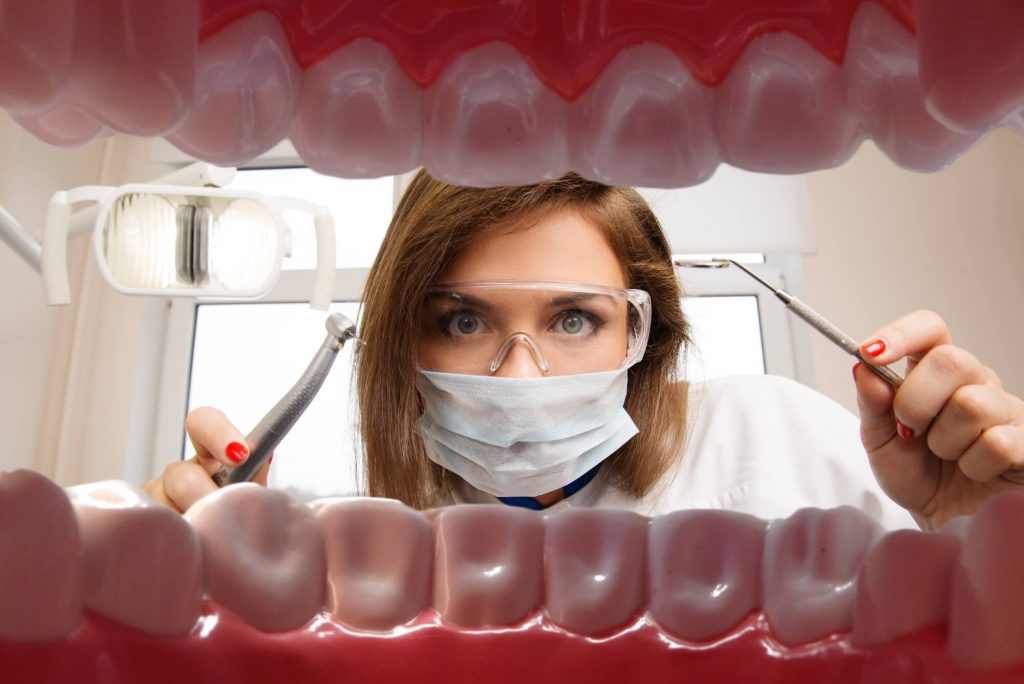 dentist looking at a patient's mouth before performing oral surgery in Sunrise